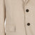 Close-up of a beige corduroy jacket with buttons and a pocket on a beige background